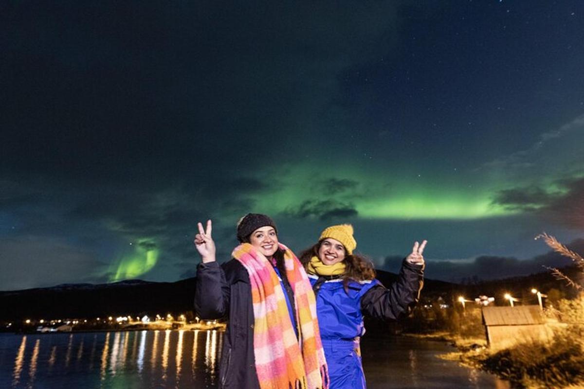 Dos personas de pie frente a la aurora boreal.