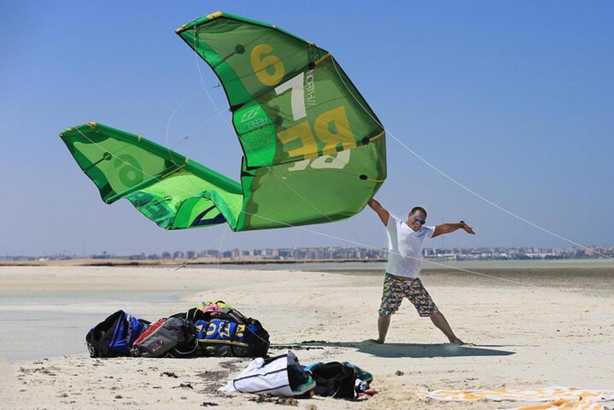 un home fent volar un estel a la platja