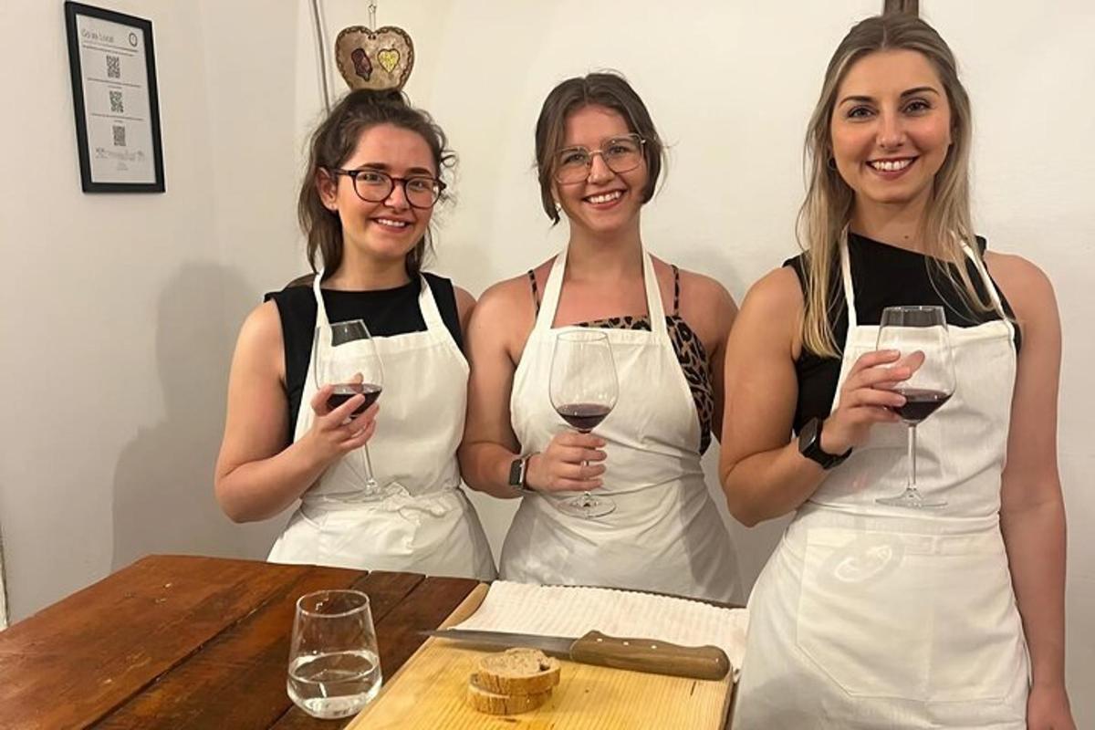 Tres mujeres con delantales sosteniendo copas de vino en una mesa