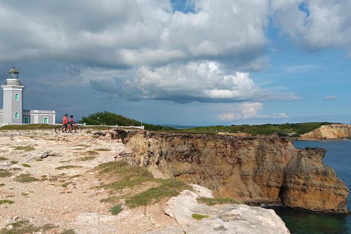 two people riding bikes on a cliff next to a lighthouse