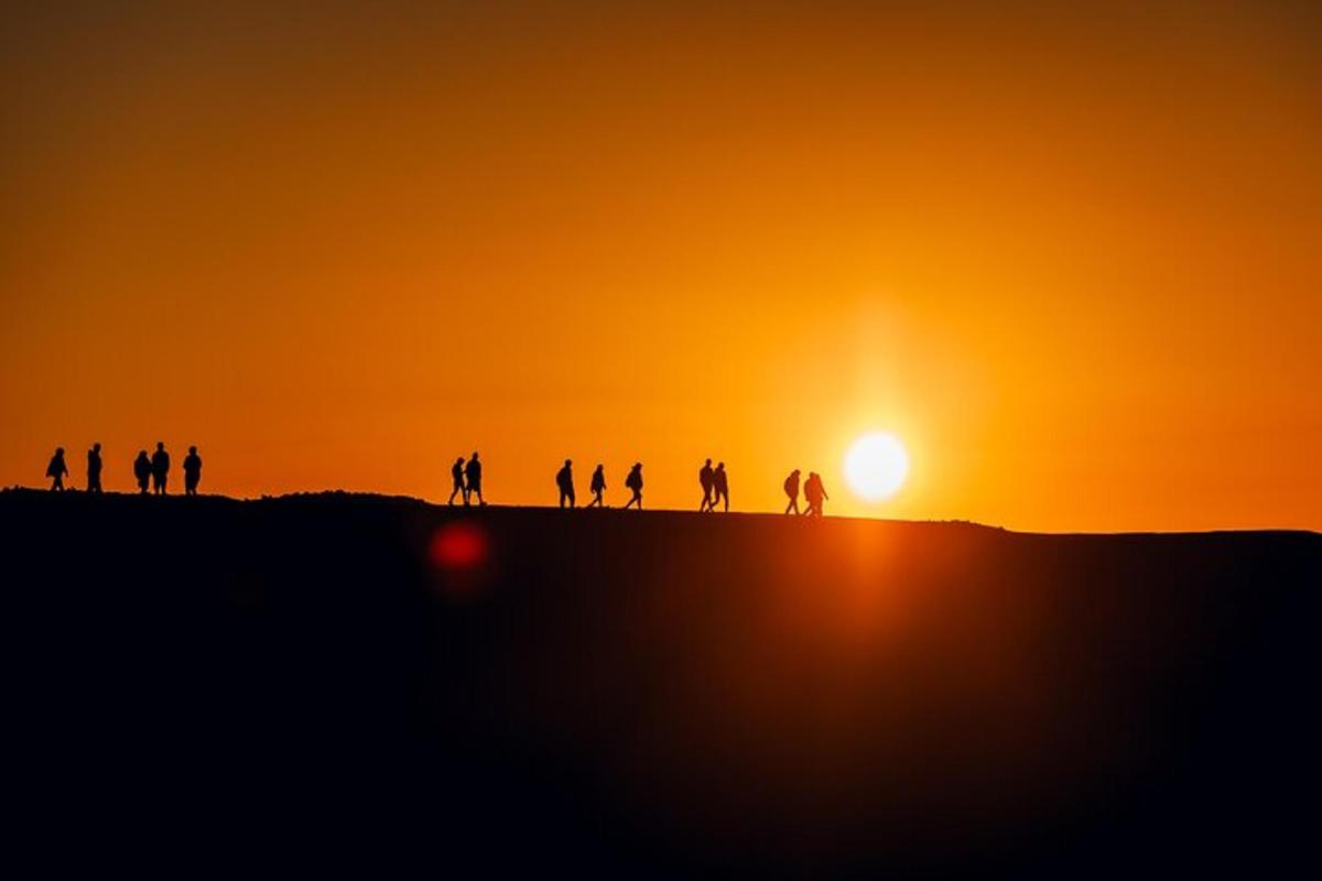 un grup de persones dretes en un turó a la posta de sol