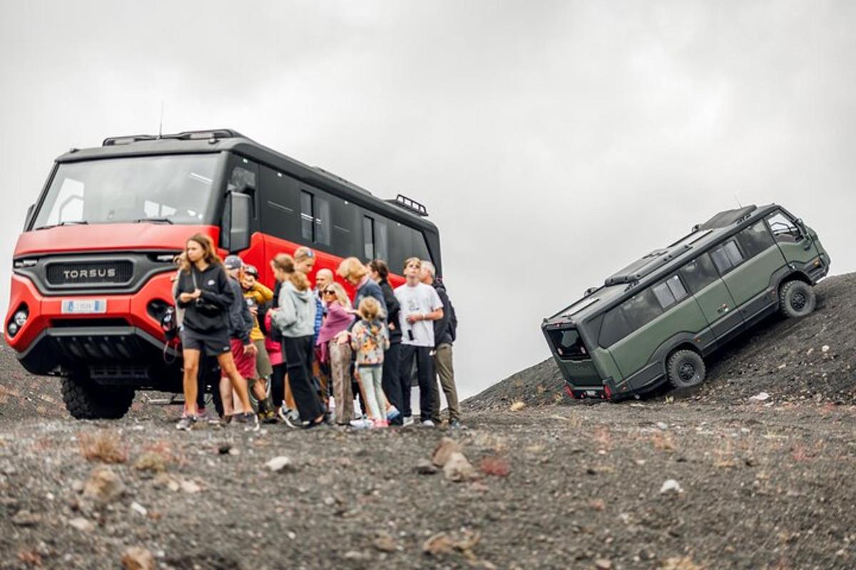 un gruppo di persone in piedi accanto a un autobus su una collina