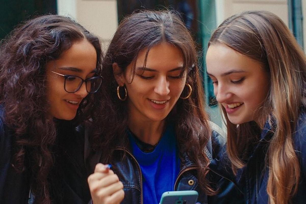 kolm noort tüdrukut vaatavad mobiiltelefoni