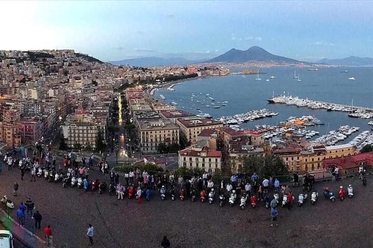 Una multitud de personas de pie alrededor de una ciudad con un puerto.
