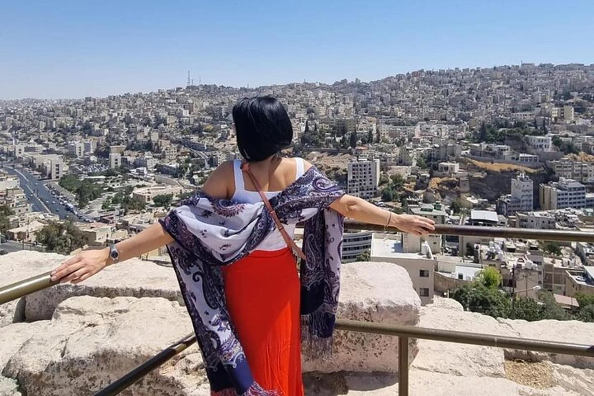 a woman standing on a ledge looking at a city