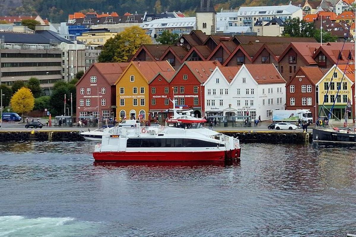 a red and white boat in the water near a city