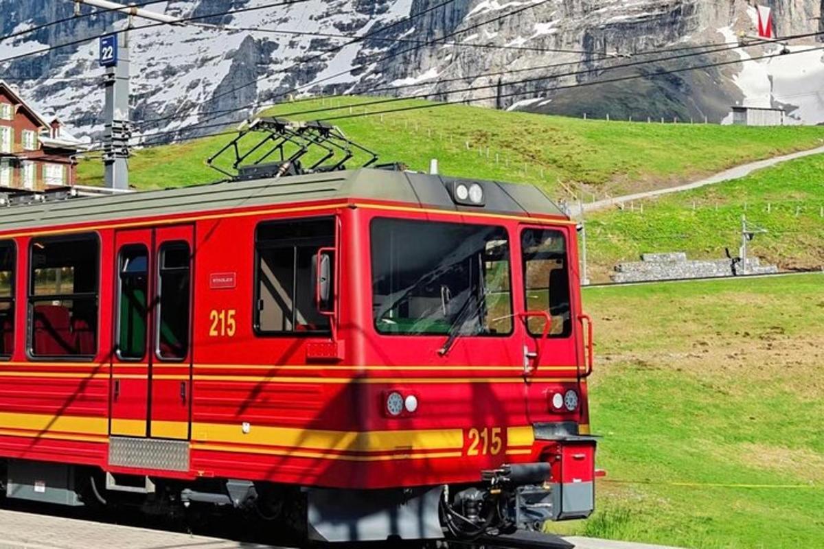 a red train traveling down the tracks near a mountain