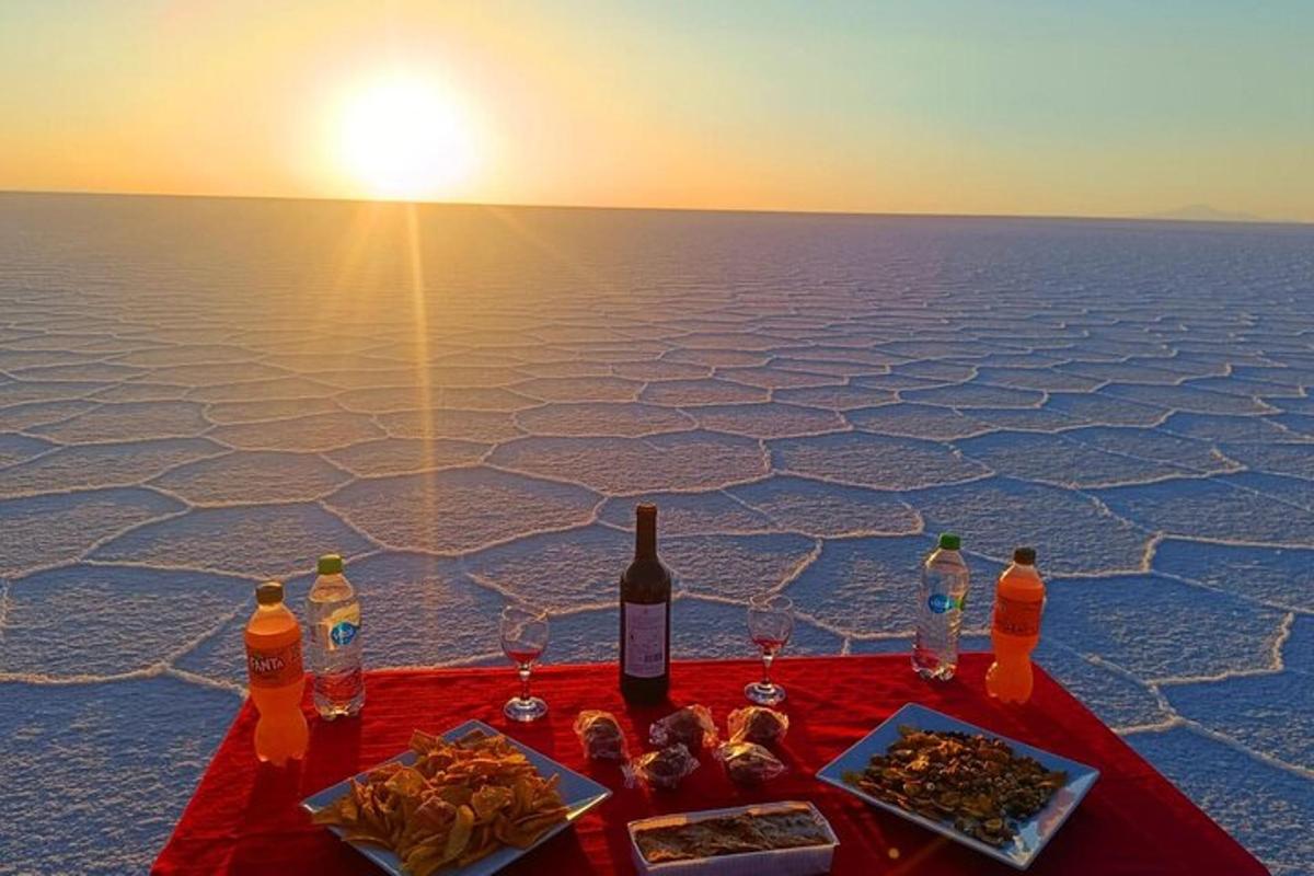 a table with wine glasses and food and the sunset