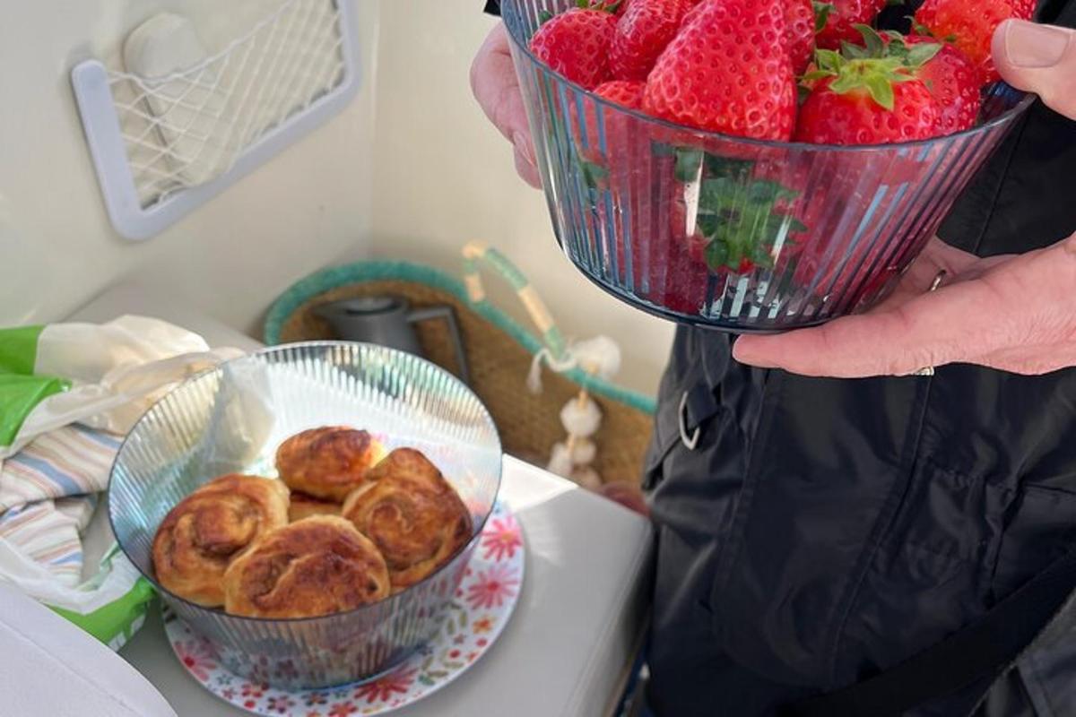 a person holding a bowl of strawberries and a bowl of pastries