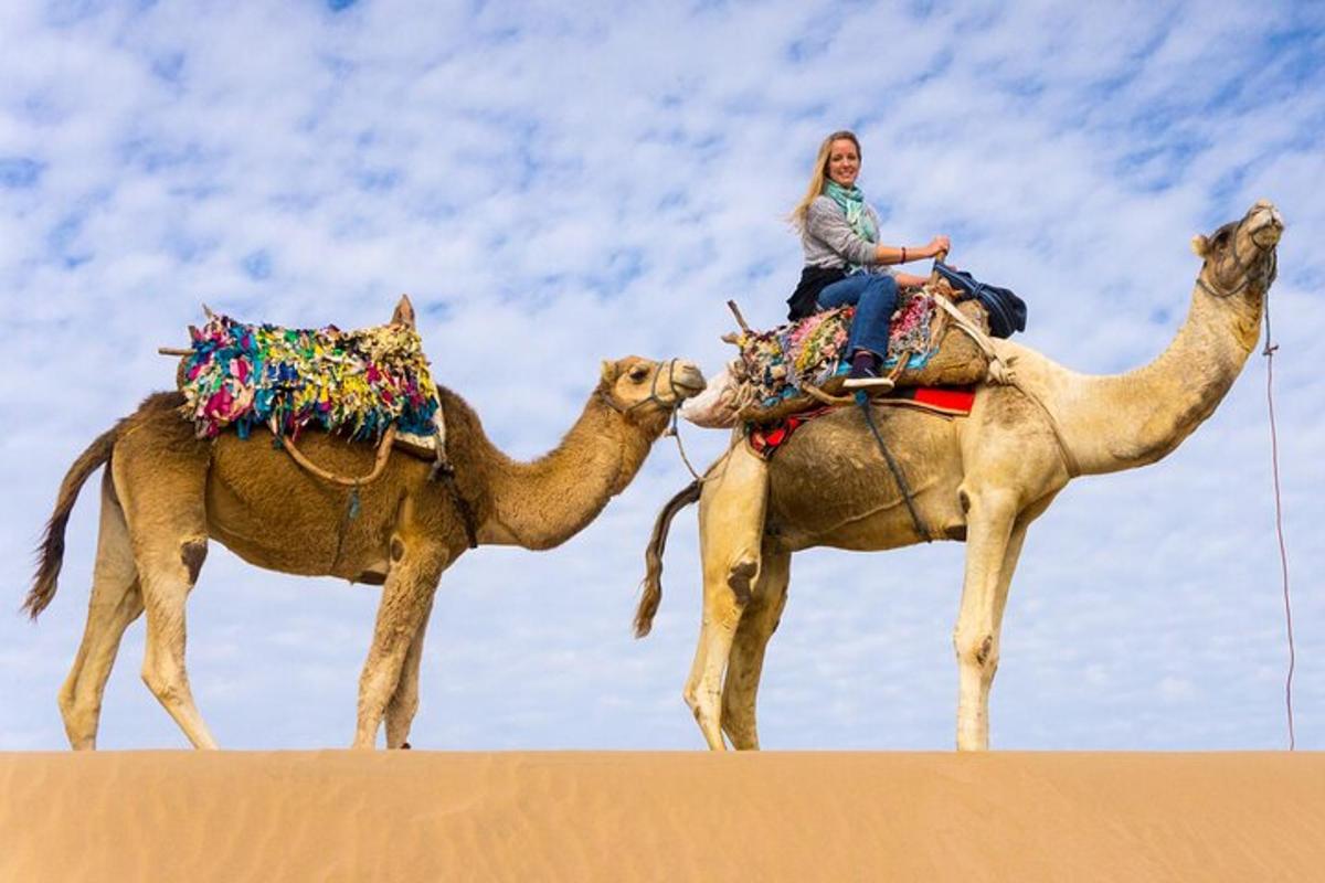 eine Frau, die auf einem Kamel in der Wüste reitet