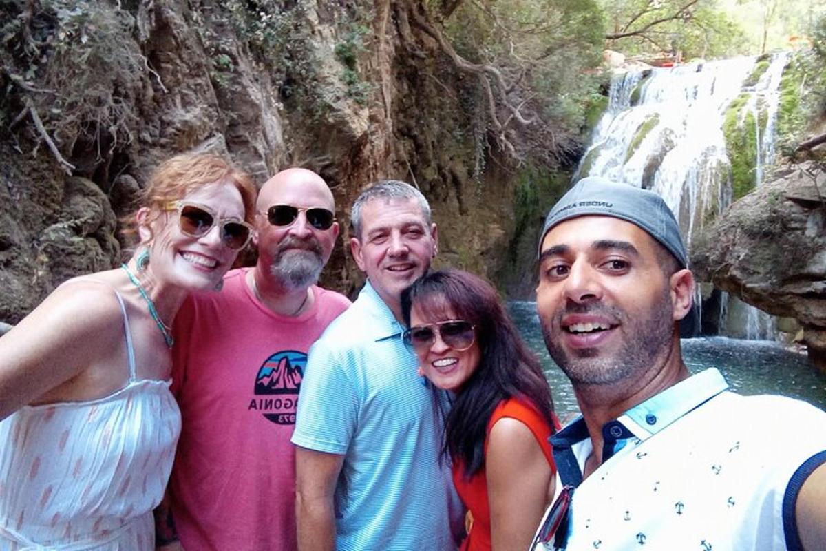 um grupo de pessoas em pé em frente a uma cachoeira