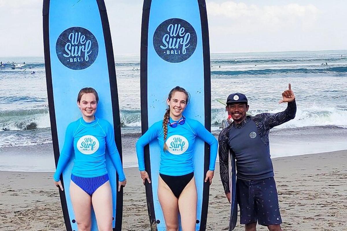 Tres personas de pie junto a tablas de surf en la playa