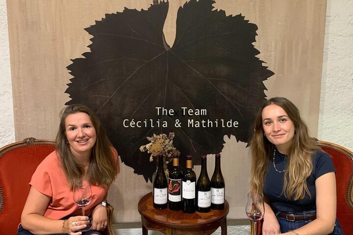două femei așezate lângă o masă cu sticle de vin