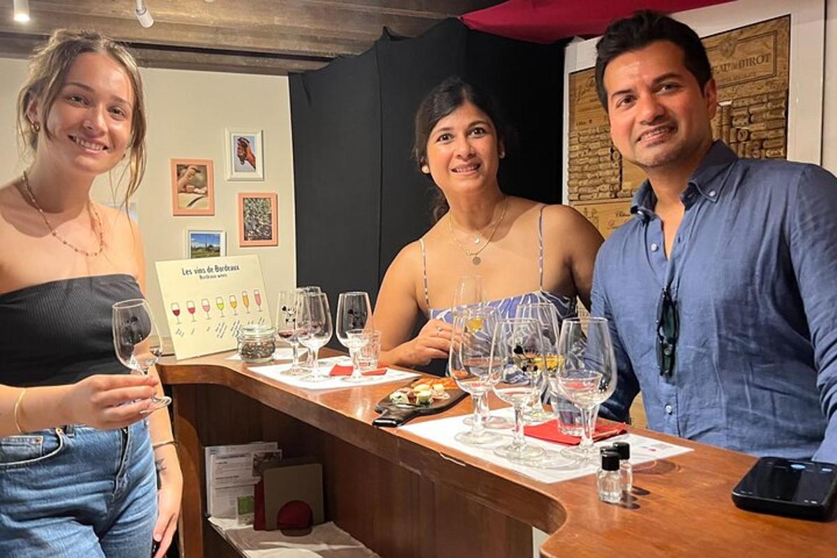 un bărbat și două femei stând la un bar cu pahare de vin