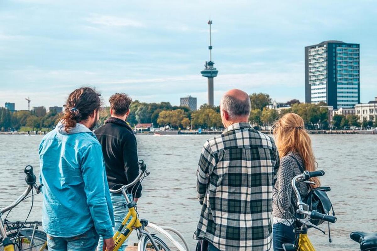 Un grupo de personas de pie junto al agua con bicicletas.