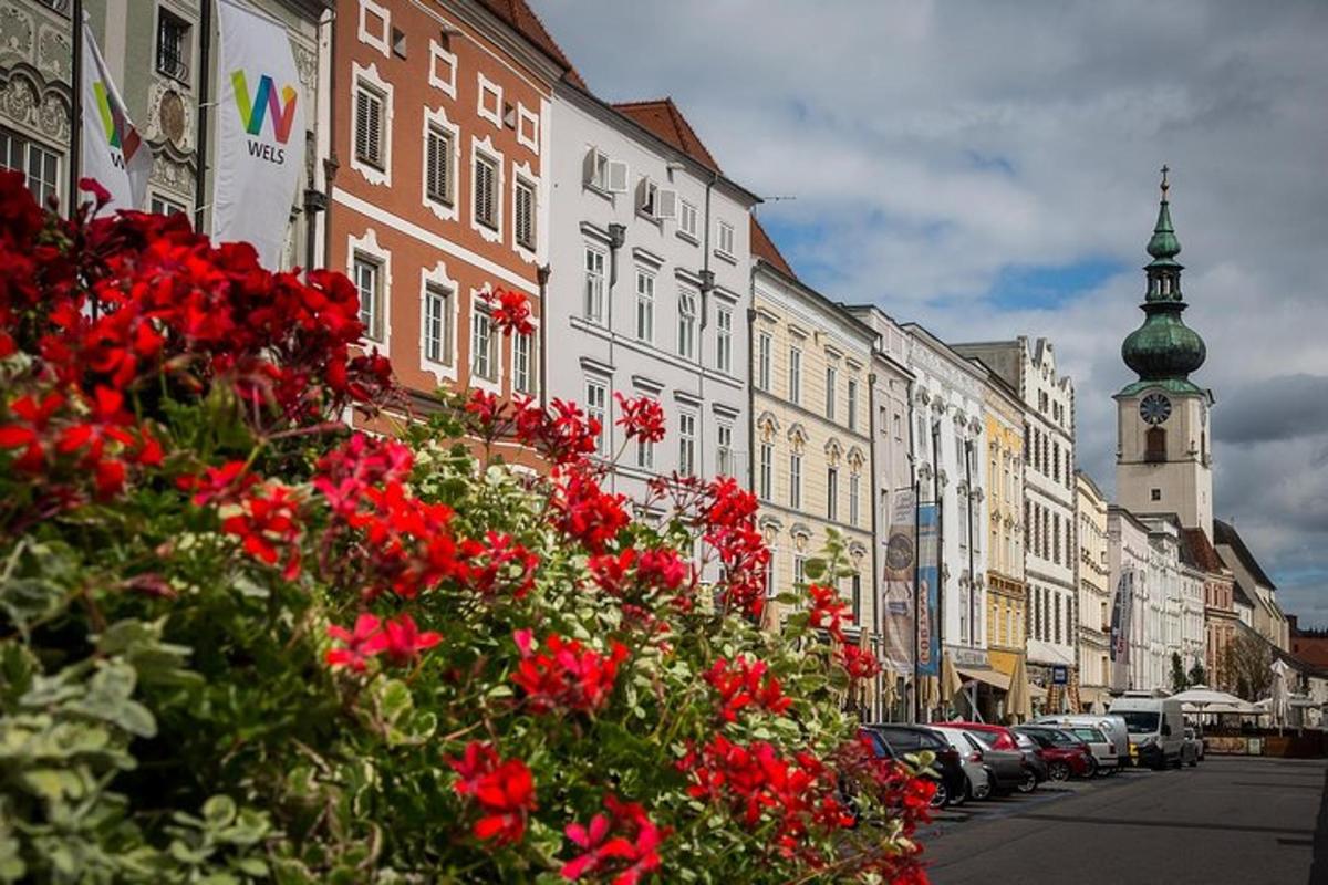 a city street with red flowers and a clock tower