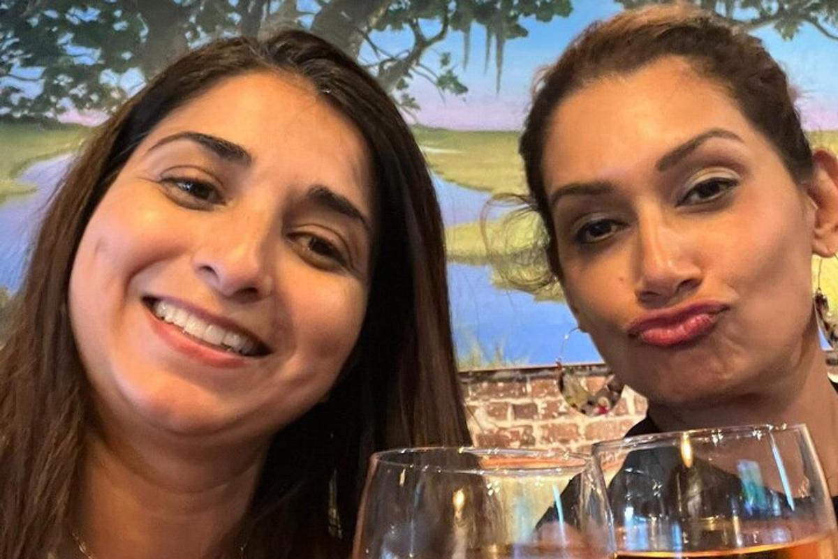 two women sitting at a table with wine glasses