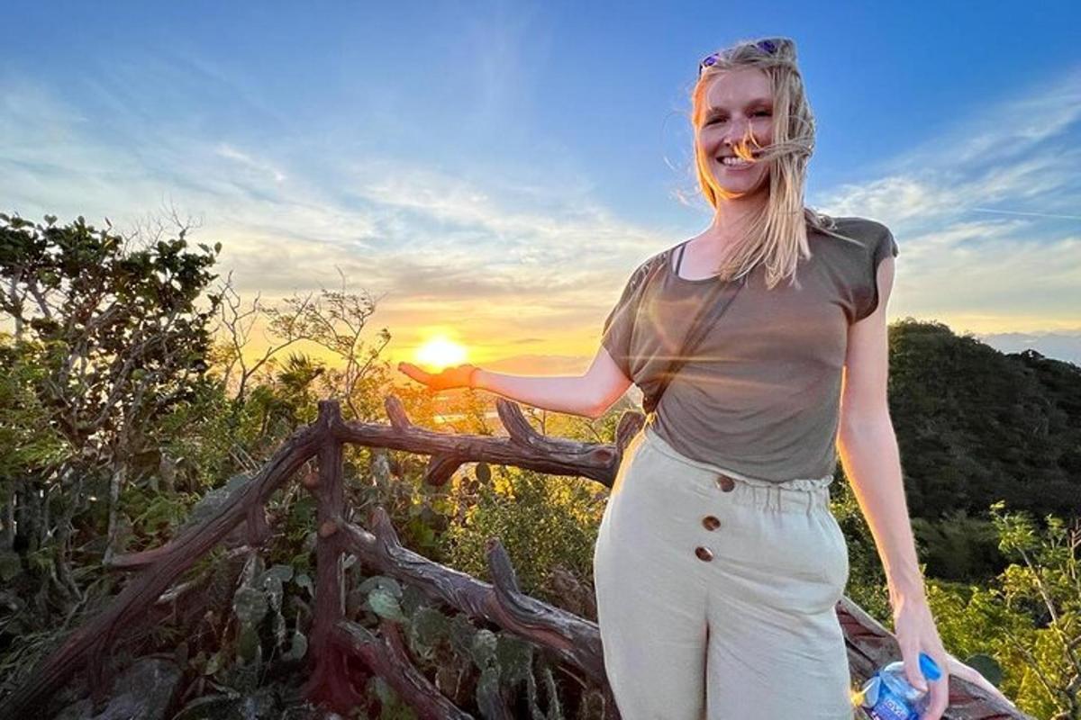 žena stojící vedle plotu se západem slunce v pozadí