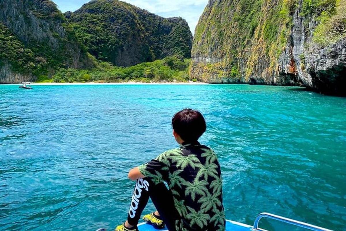 a boy sitting on the front of a boat in the water