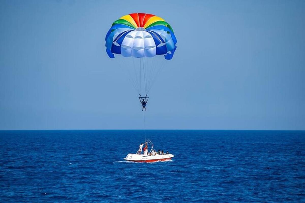un paracaigudes de colors volant sobre un vaixell a l'oceà