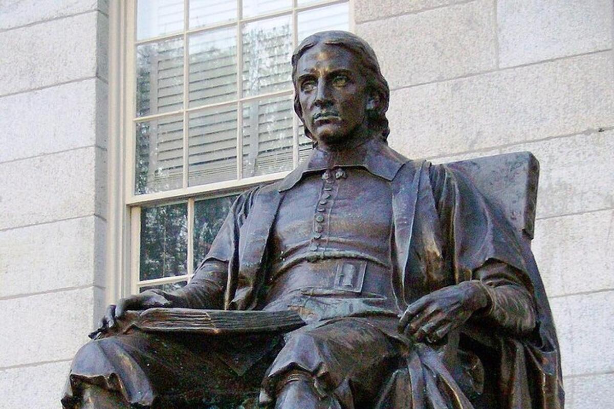 uma estátua de um homem sentado em frente a um prédio