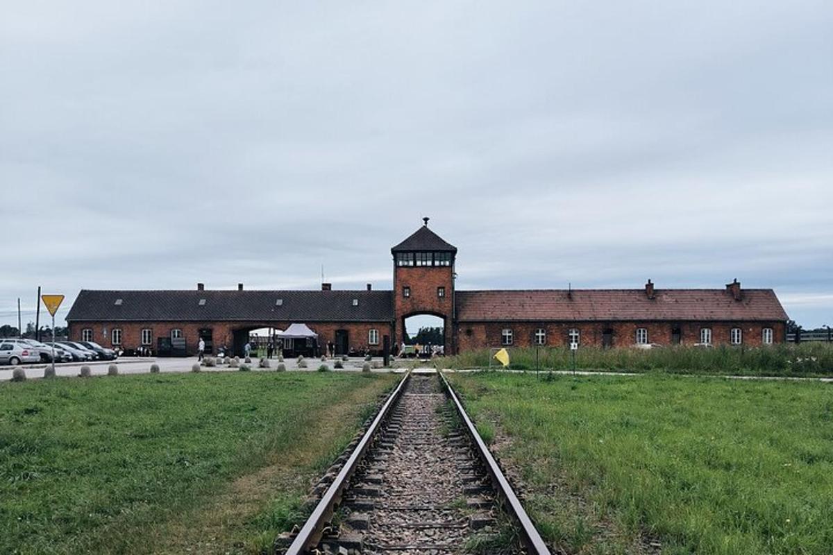 velká cihlová budova s hodinovou věží a železničními kolejemi