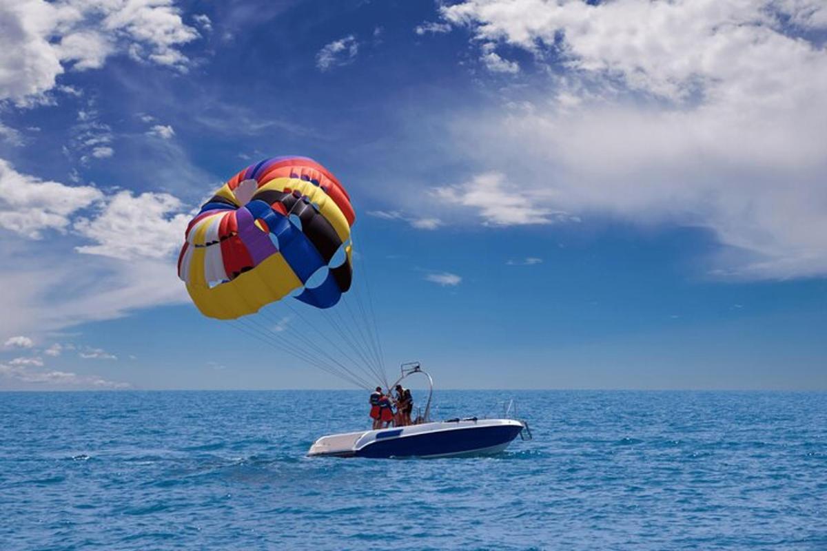 two people on a boat with a parachute in the ocean