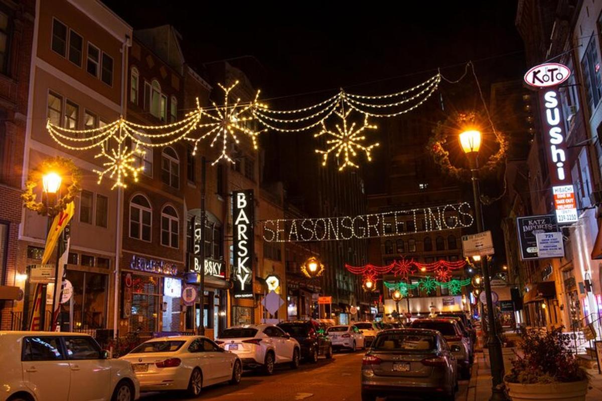 a city street with cars parked on the street with christmas lights