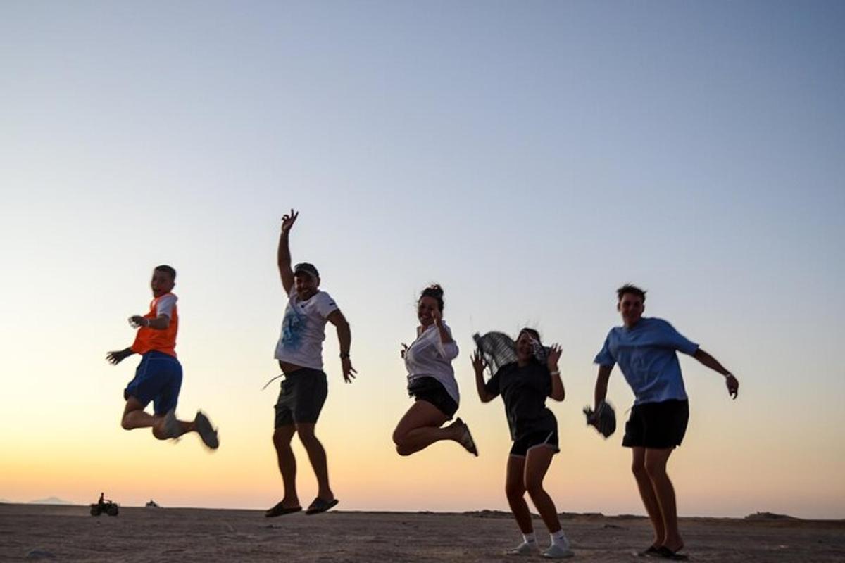 un gruppo di persone che saltano sulla spiaggia al tramonto