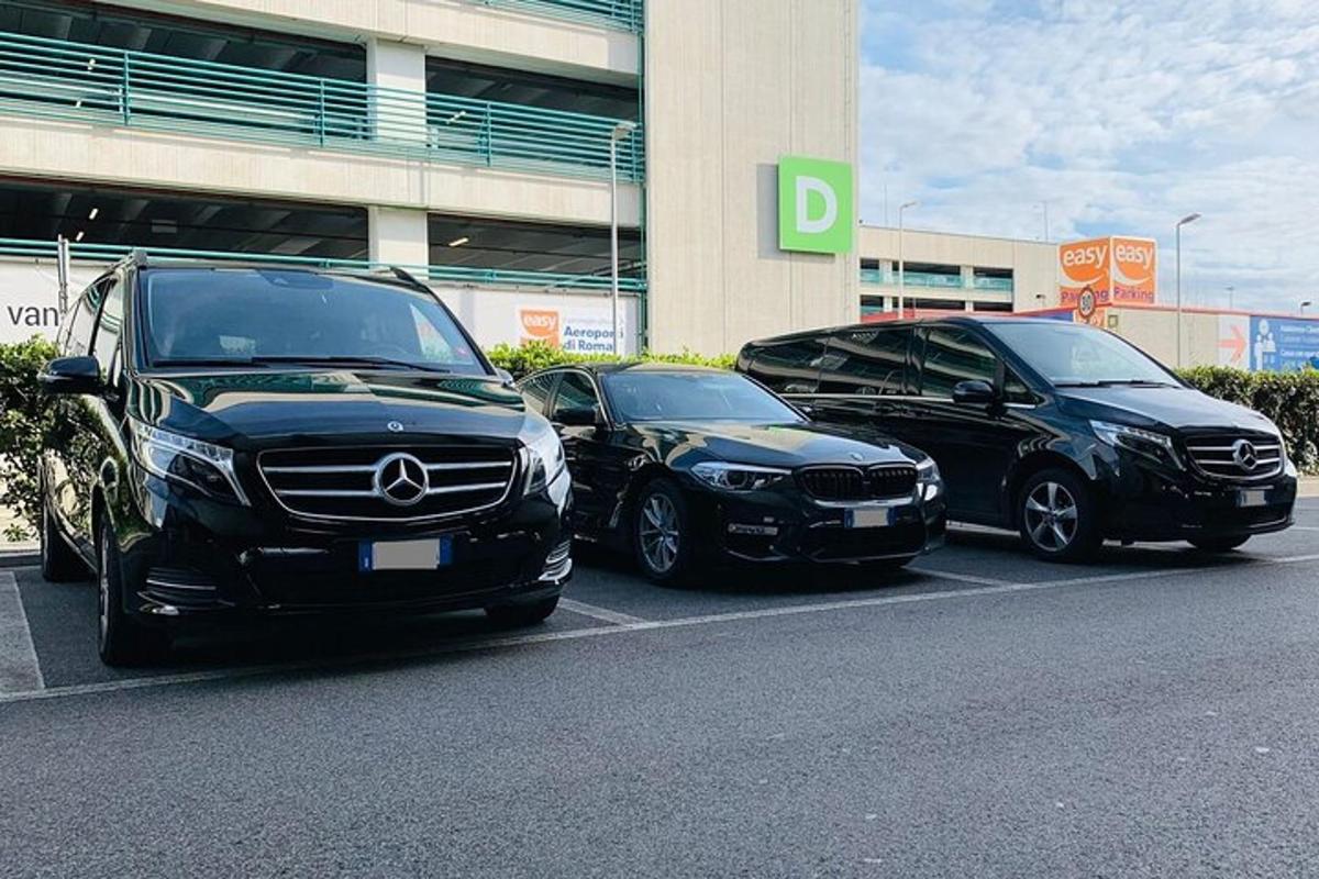 trīs automašīnas novietotas stāvvietā ēkas priekšā