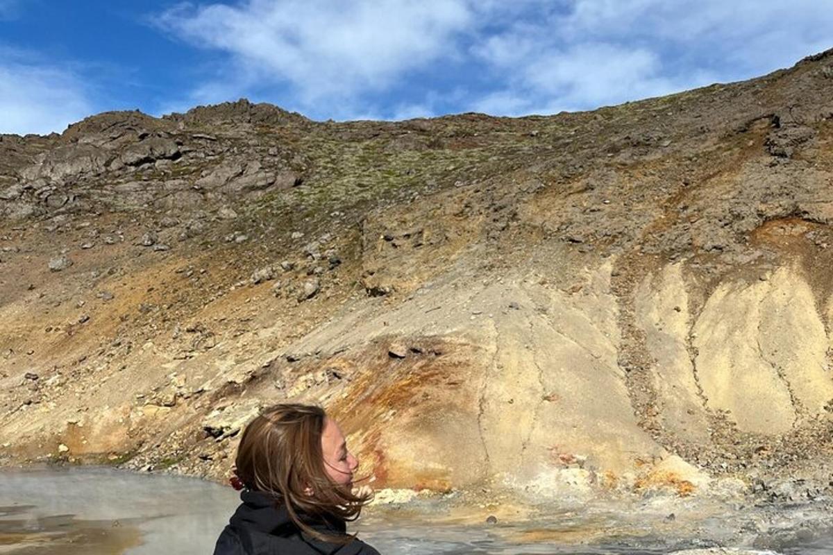 kona stendur í vatninu við fjall