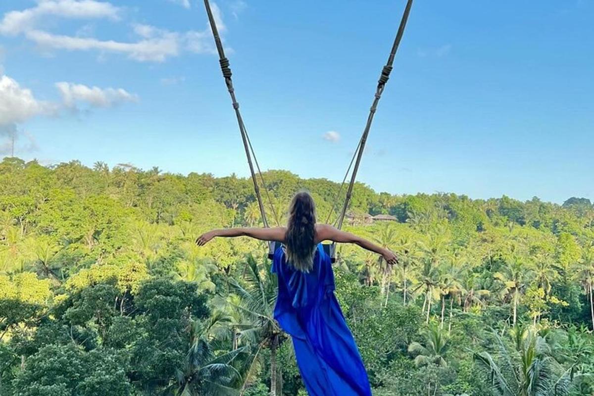 una donna in un vestito blu che si dondola su un'altalena di corda