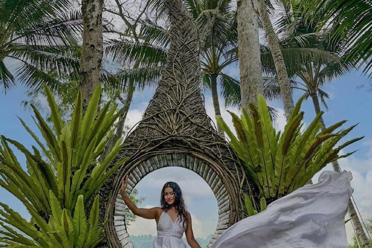 una donna in piedi sotto un arco di legno davanti a una palma