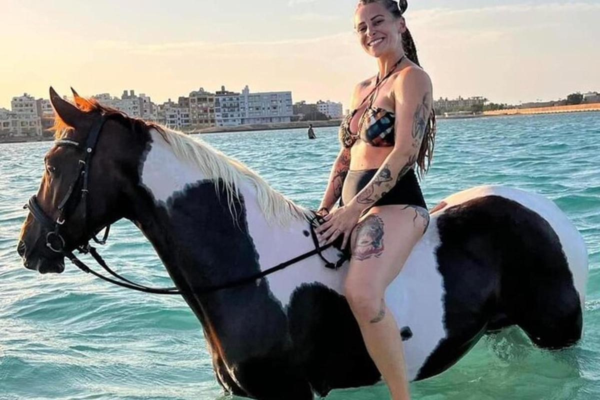 žena v bikinách jedoucí na koni ve vodě