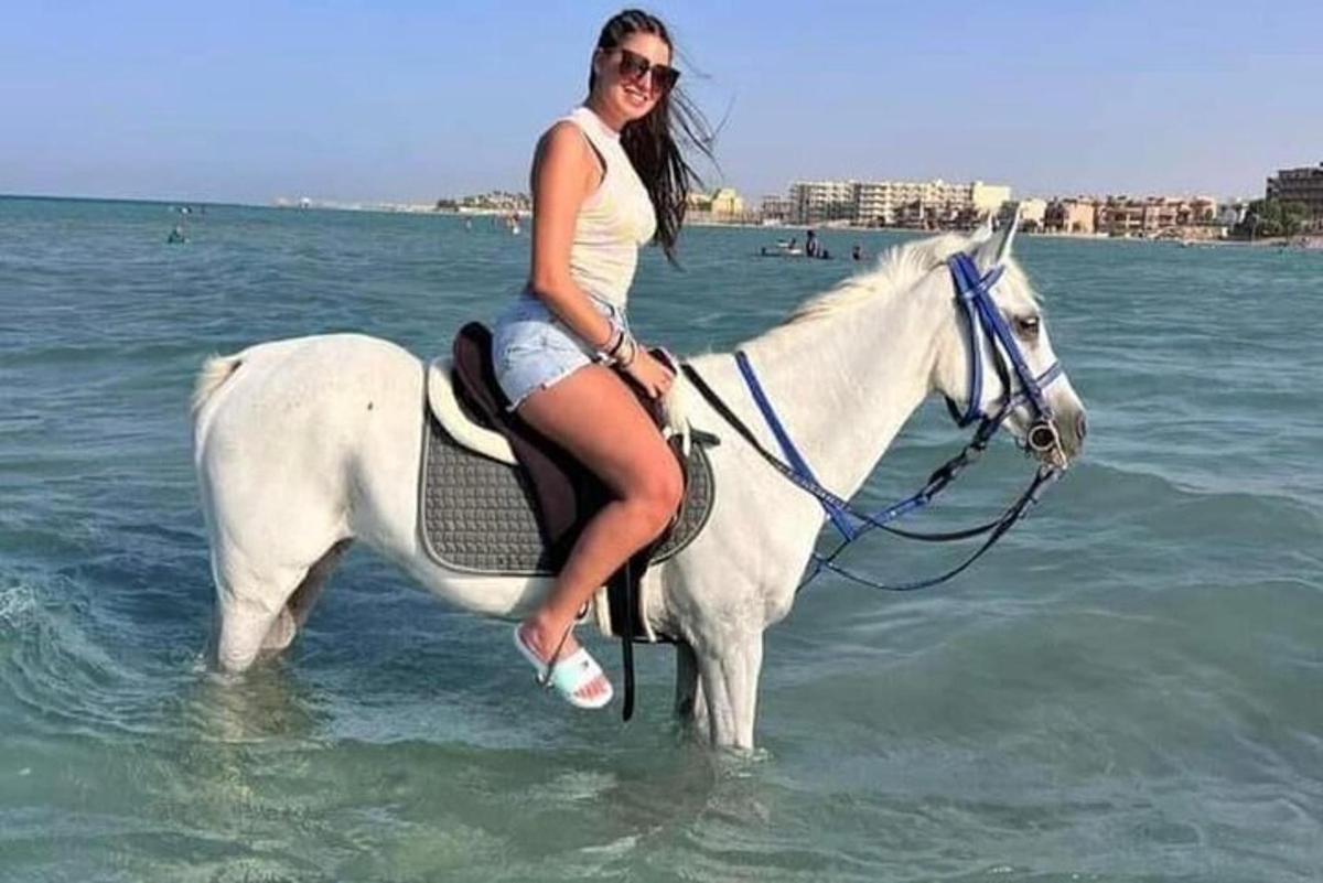 o femeie călare pe un cal alb în ocean