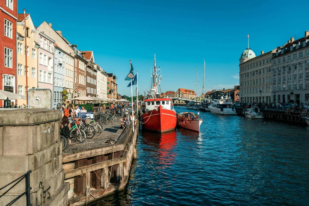 Rauður bátur liggur að bryggju í skurði með byggingum