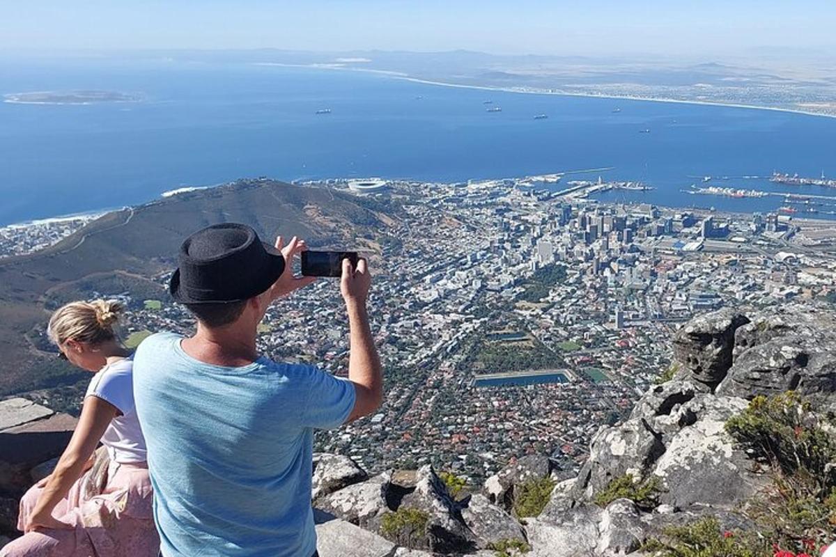 Un hombre tomando una fotografía de una ciudad desde una montaña.
