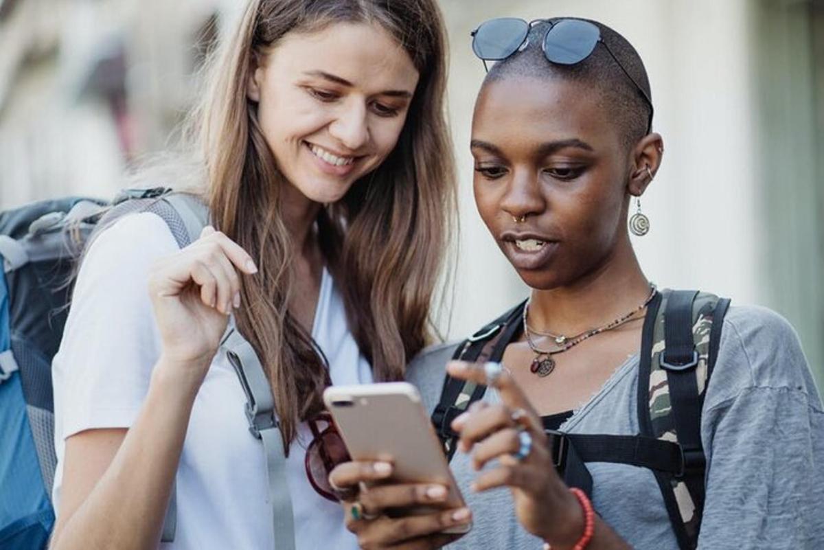 dve mladi ženski, ki gledata v mobilni telefon
