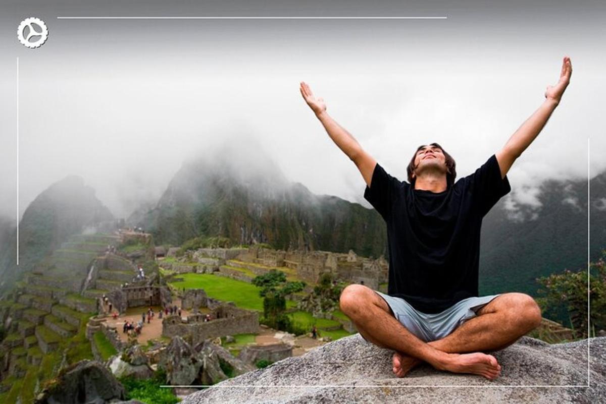 một người đàn ông ngồi trên mép núi với hai tay giơ lên