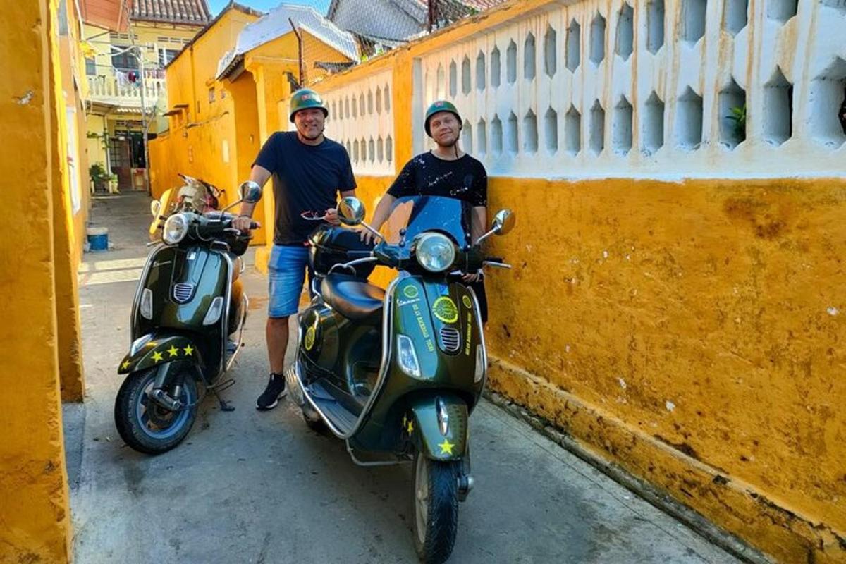 muž stojí vedle motorového skútru