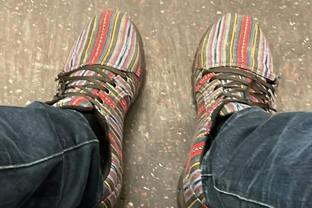 a persons feet with striped socks and shoes on the ground