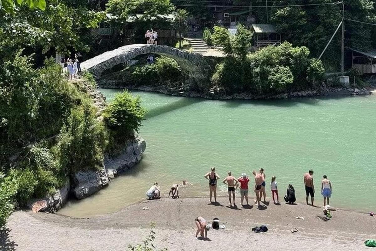 a group of people standing on a beach near a river