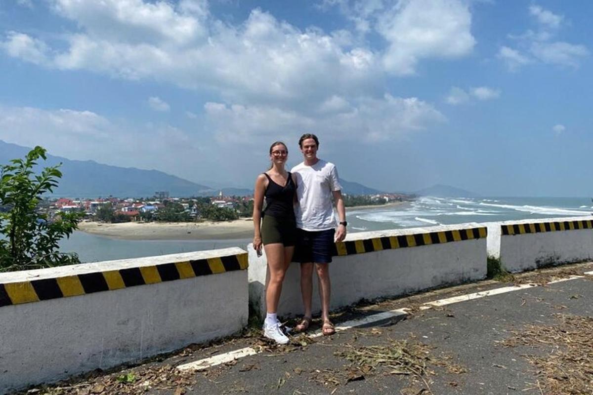 un uomo e una donna in piedi su un muro vicino all'oceano