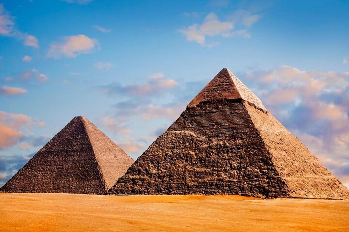 Dvě pyramidy na poli pod zataženou oblohou