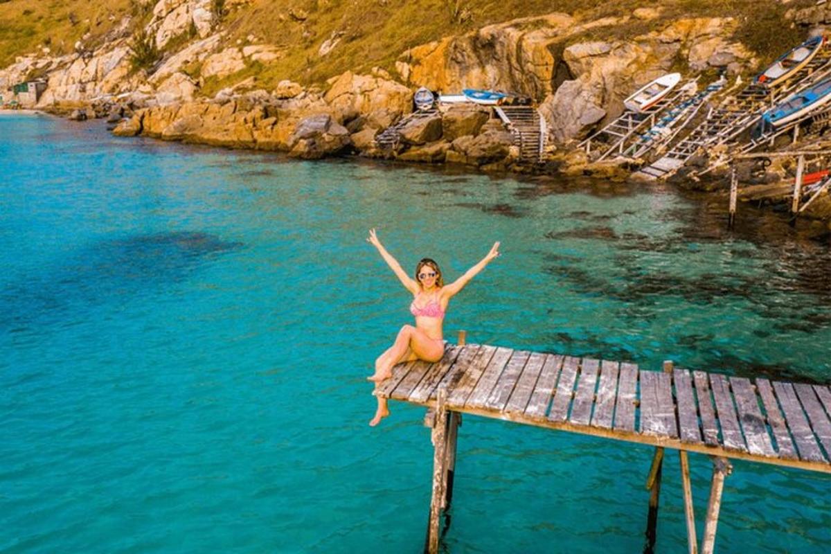 Una mujer en bikini sentada en un muelle en el agua.