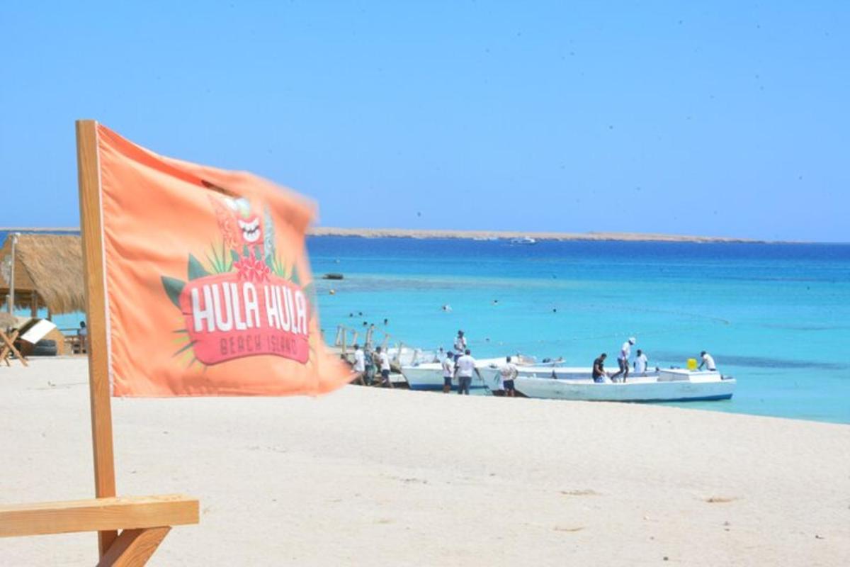 una bandera en una playa con un barco en el agua