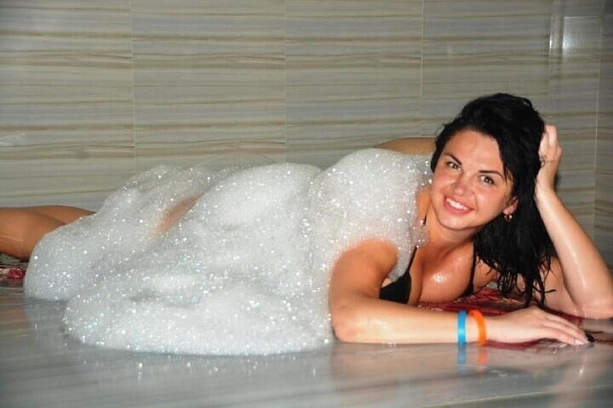 Una mujer tumbada en una bañera cubierta de burbujas.