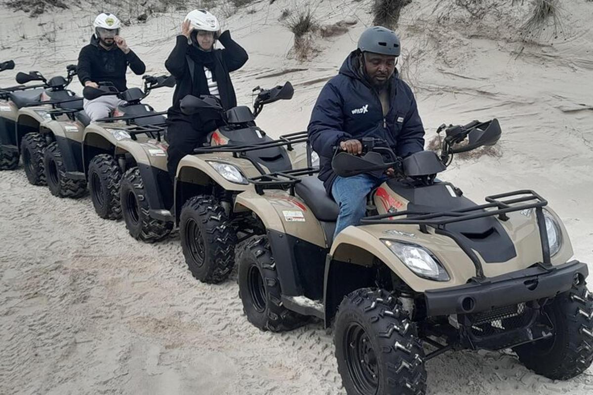 un grup de persones conduint quads a la sorra