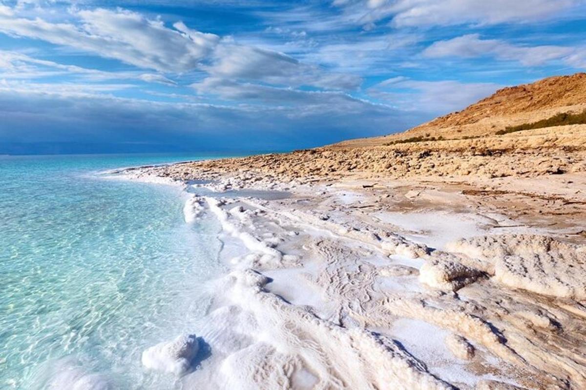 a sandy beach with the ocean and a cloudy sky