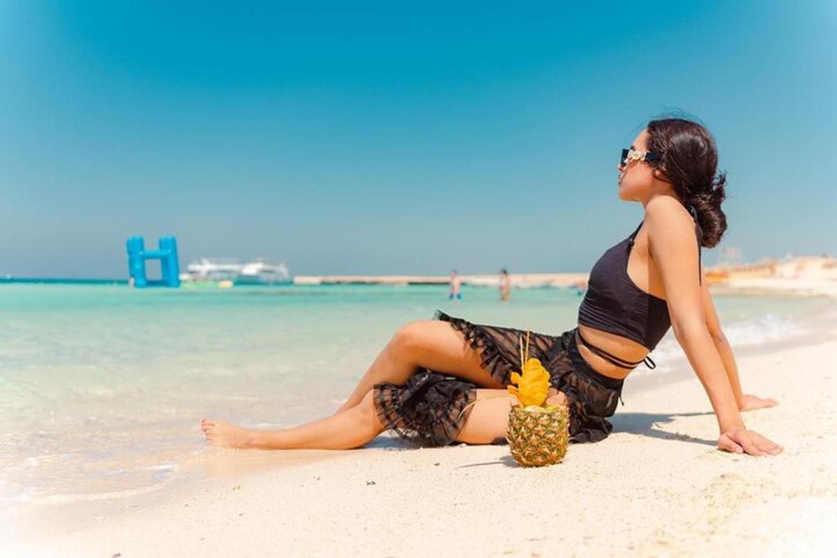 a woman in a bikini sitting on a beach with a pineapple